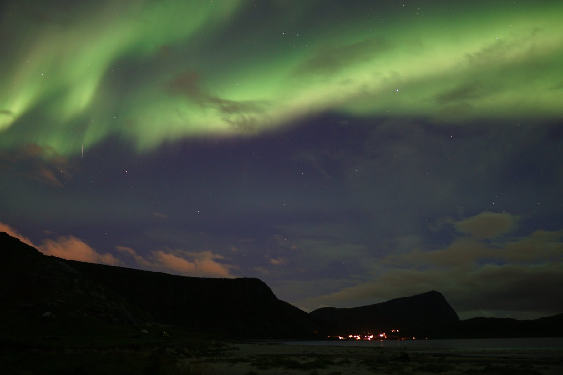 Aurora boreale verde sopra le montagne della spiaggia di Haukland, alle Lofoten