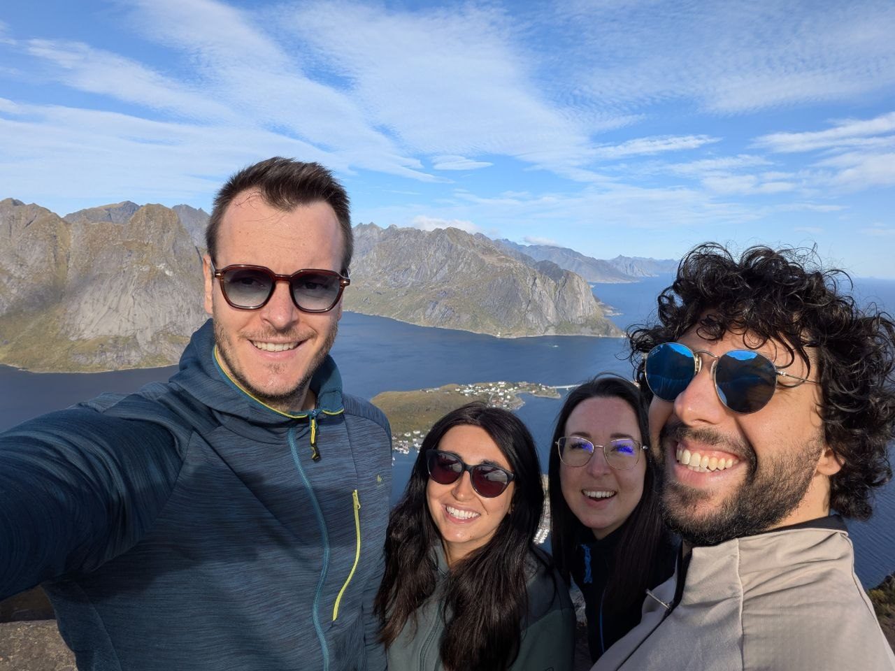Veronica, Andrea, Roberta e Giuseppe sorridenti in cima a una montagna alle Lofoten, con i fiordi alle spalle